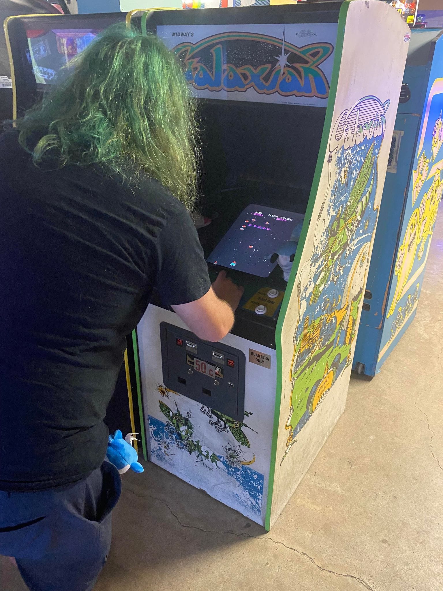 A man with green hair plays a Galaxian arcade game, Photo 2